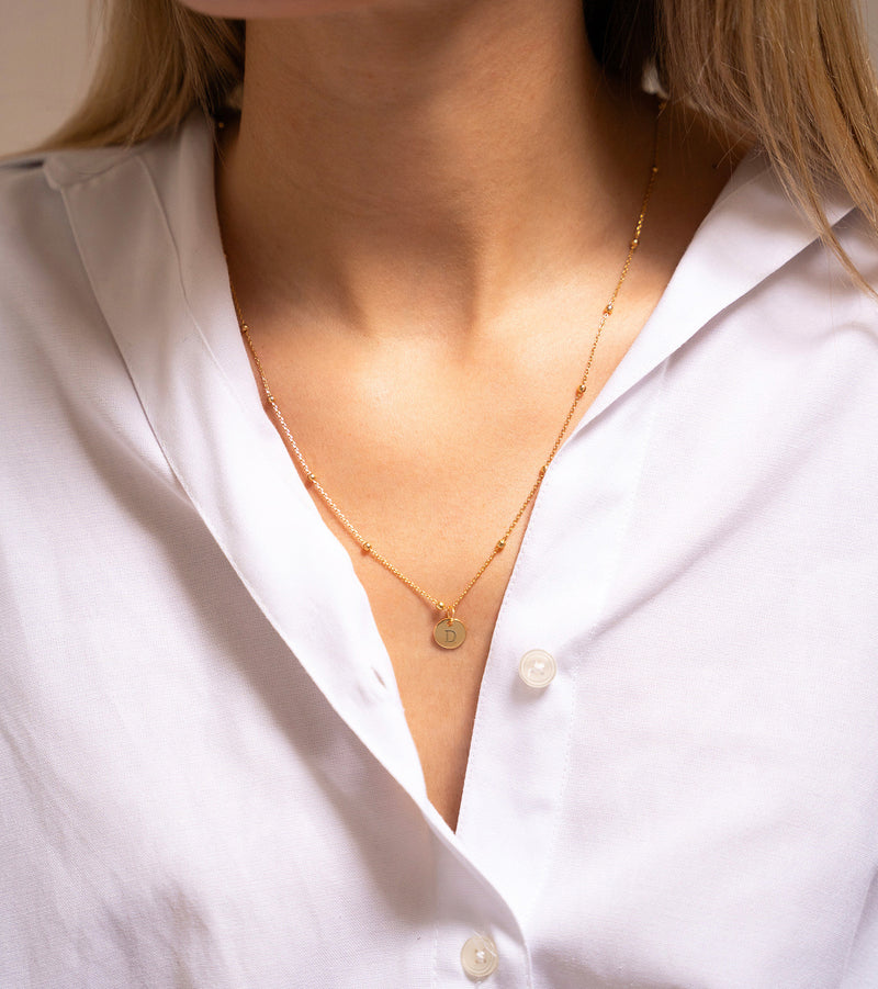 Un charmant pendentif de 10mm en plaqué or, orné de votre inscription préférée, pour une pièce unique qui vous distingue.