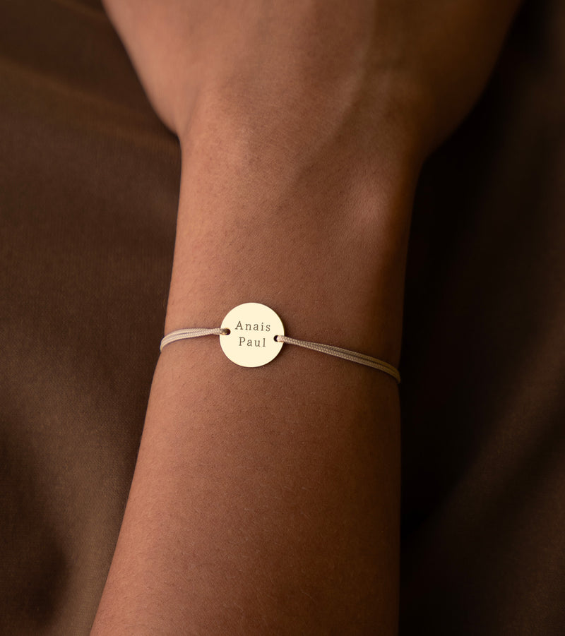  bracelet personnalisé, arborant une médaille plaquée or de 15mm, deux trous pratiques, et un cordon beige.