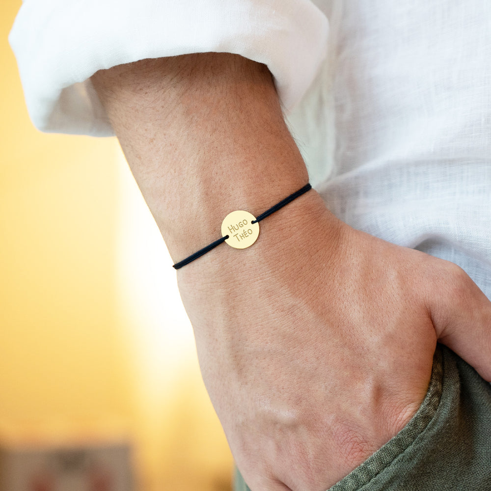 bracelet en plaqué or avec une médaille personnalisée de 15mm avecdeux trous et un cordon noir incarne l'élégance.