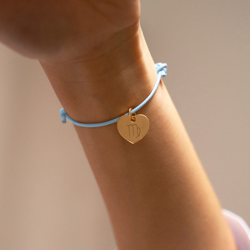 Un magnifique bracelet personnalisé, mettant en valeur un charmant cœur doré de 15mm, sur un cordon en bleu pastel, symbole de tendresse et d'affection.
