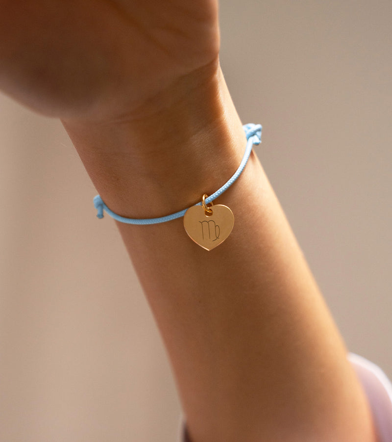 Un magnifique bracelet personnalisé, mettant en valeur un charmant cœur doré de 15mm, sur un cordon en bleu pastel, symbole de tendresse et d'affection.