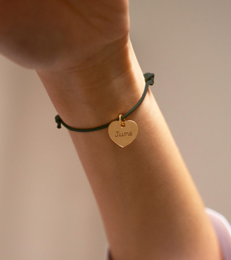 Un bracelet plaqué or, orné d'un cœur de 15mm, personnalisé sur un cordon kaki.