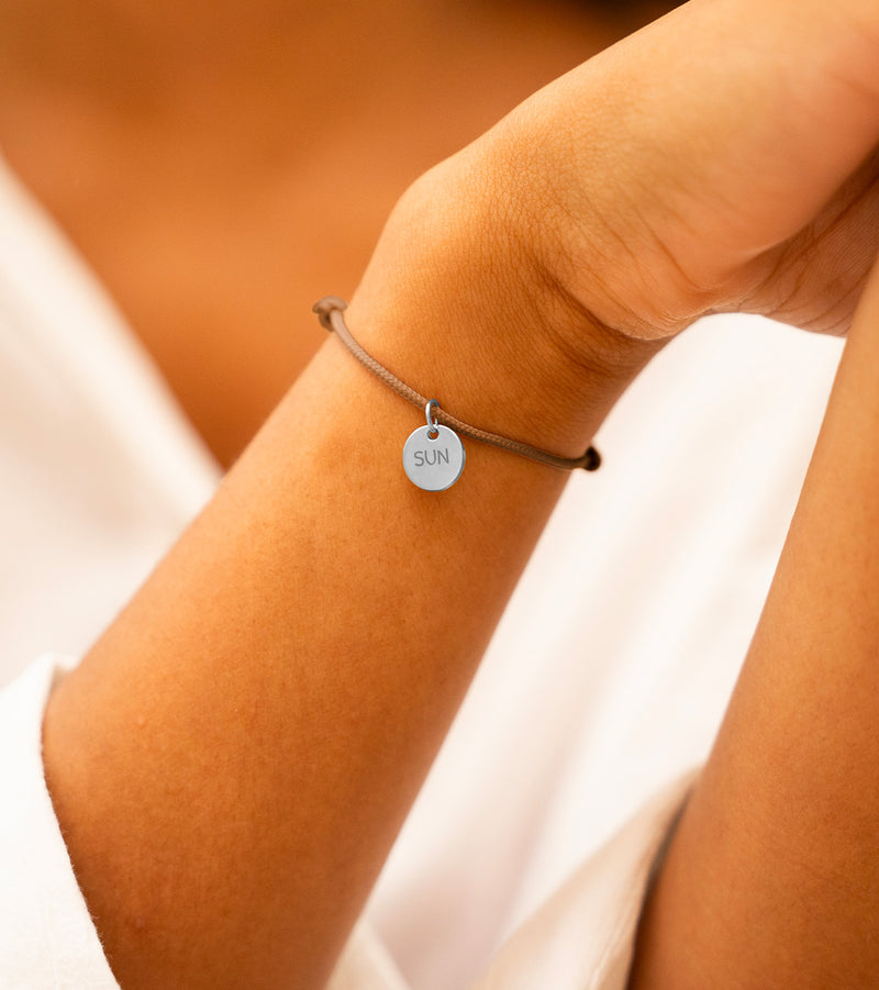 Bracelet argenté avec médaille 10mm personnalisée, sur cordon marron clair, ajoutant une note personnelle à votre look.