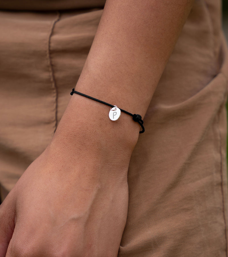 Accessoire chic, bracelet personnalisé orné d'une médaille argentée de 10mm sur cordon noir.