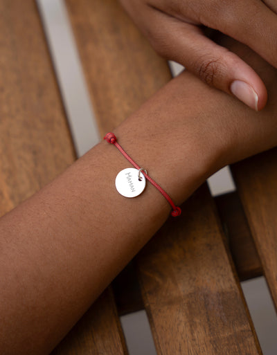 Bracelet personnalisé en argent orné d'une médaille de 15mm, agrémenté d'un cordon rouge distinctif.
