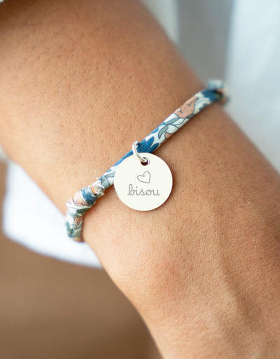 Un bracelet argenté avec une médaille de 15mm sur un lien Liberty lilas.