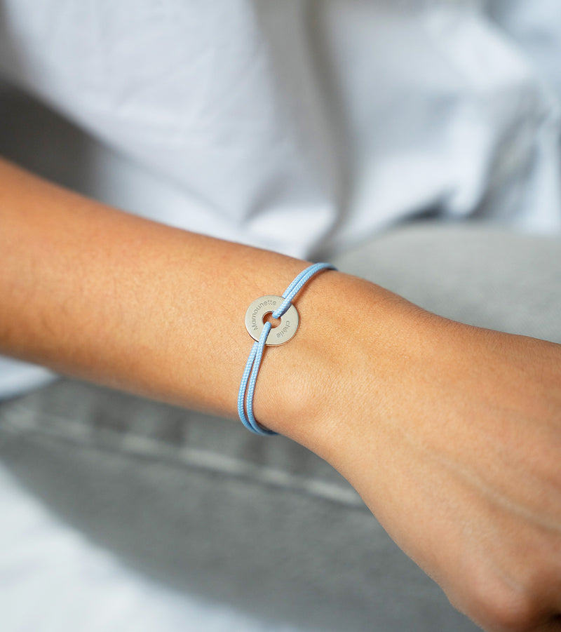 Avec un cordon bleu pastel, ce bracelet en forme de cible est personnalisé de 15mm en argent.