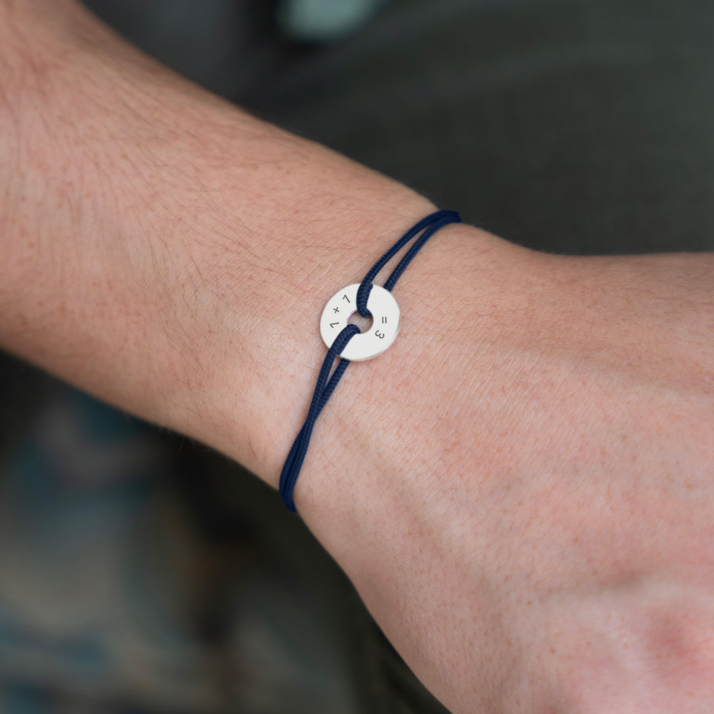 Ce bracelet, conçu en forme de cible, présente une personnalisation de 15mm en argent et un cordon bleu marine.
