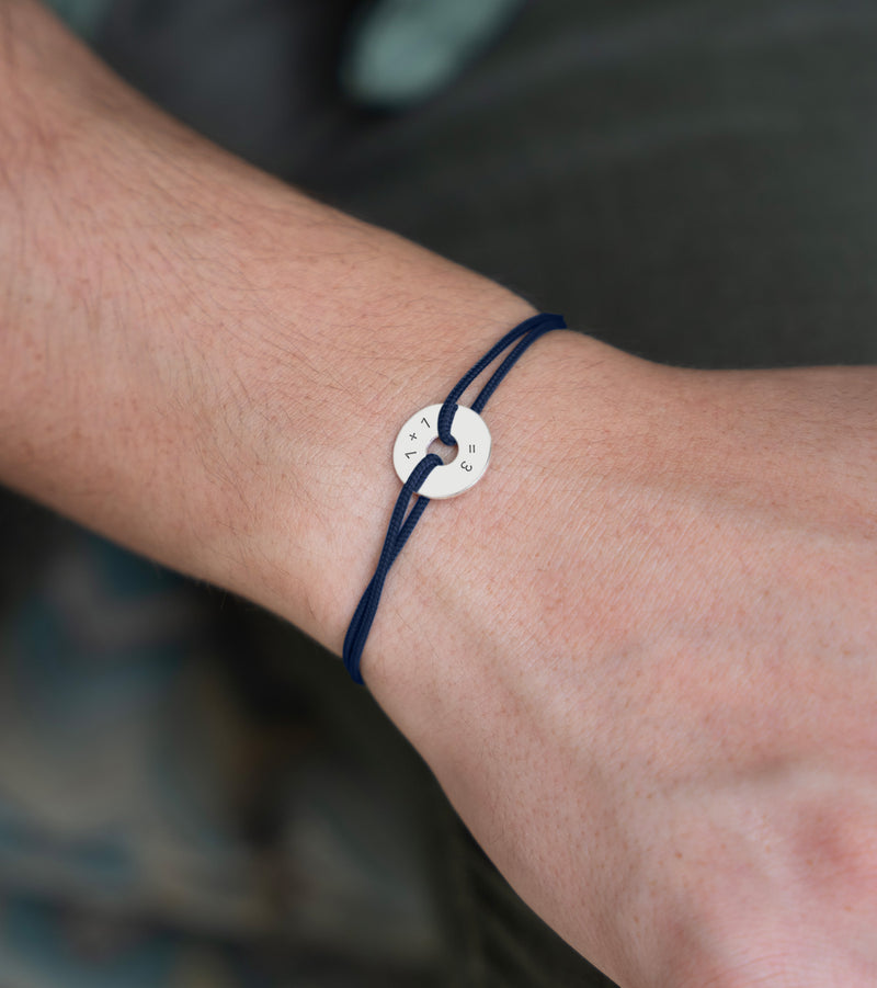 Ce bracelet, conçu en forme de cible, présente une personnalisation de 15mm en argent et un cordon bleu marine.