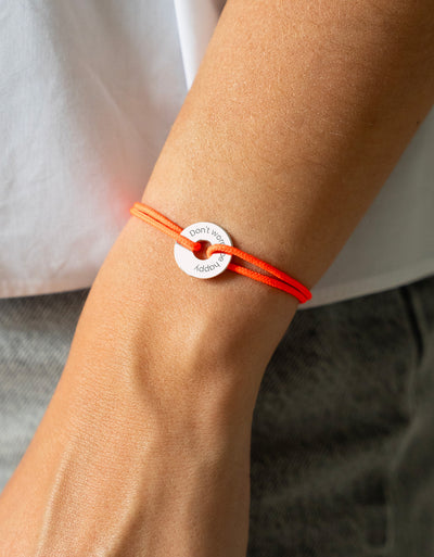 Personnalisé de 15mm en argent, ce bracelet en forme de cible est rehaussé d'un cordon orange fluo.