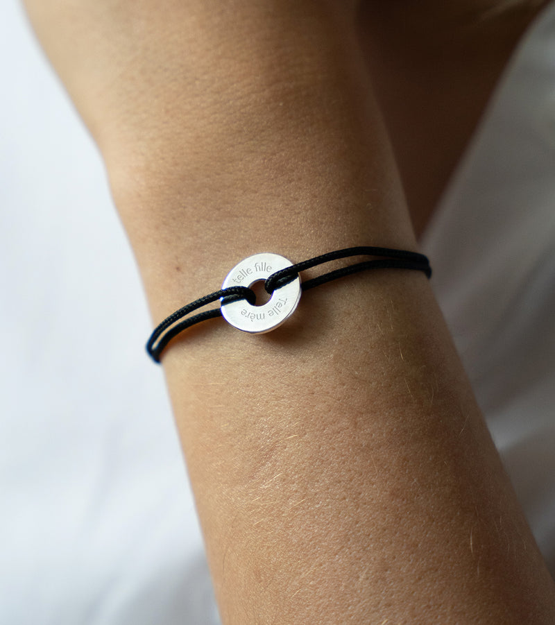Avec son cordon noir, ce bracelet en forme de cible est personnalisé de 15mm en argent.