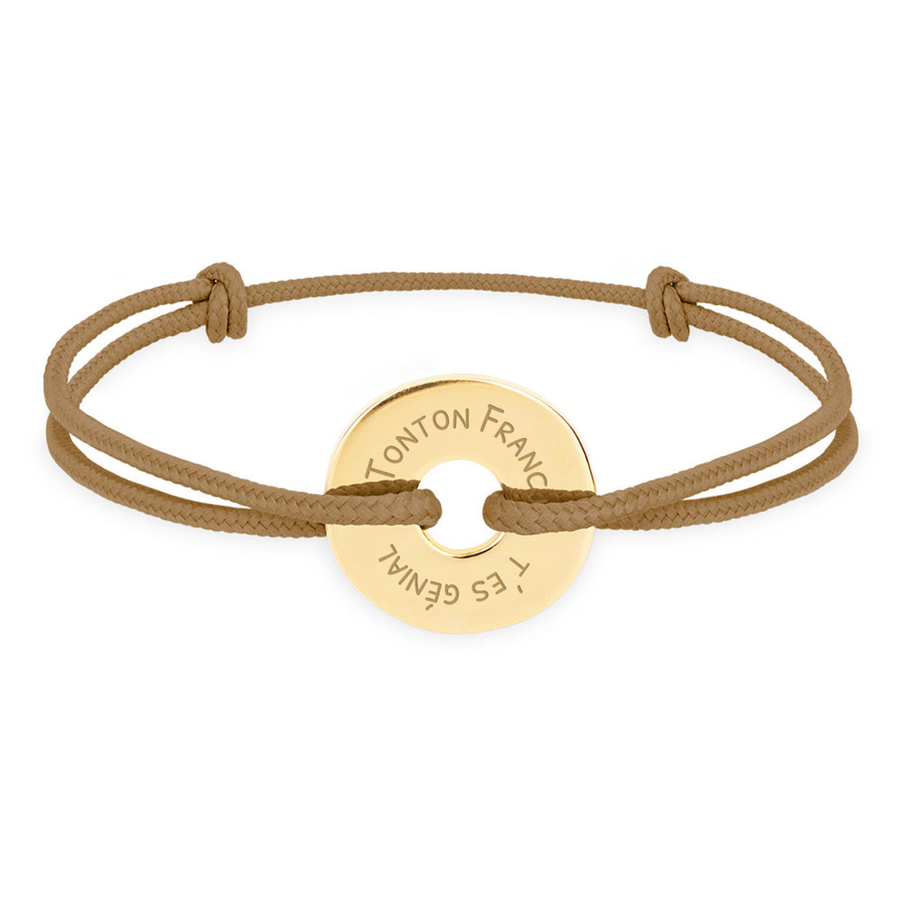 Ce bracelet plaqué or, en forme cible de 15mm, personnalisé selon vos envies, est complété par un cordon marron clair.