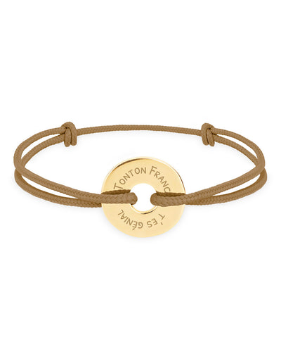 Ce bracelet plaqué or, en forme cible de 15mm, personnalisé selon vos envies, est complété par un cordon marron clair.