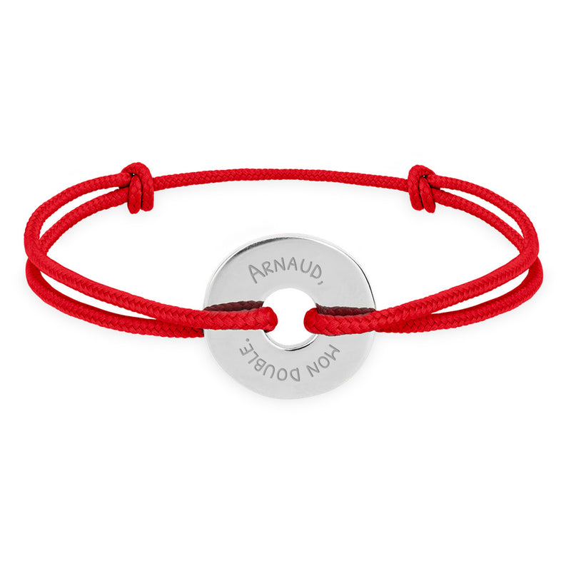 Ce bracelet en forme de cible, avec un cordon rouge, est personnalisé de 15mm en argent.