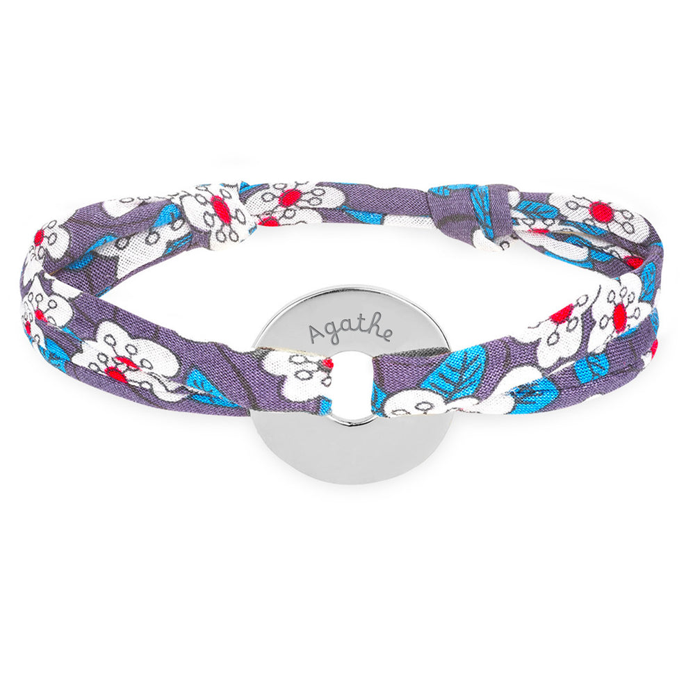 Un bracelet en forme de cible, personnalisé de 15mm en argent, lié par un tissu Liberty Iris.