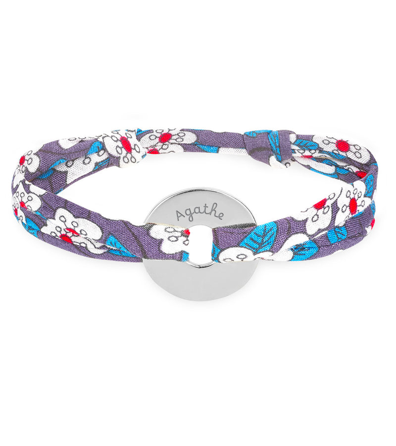 Un bracelet en forme de cible, personnalisé de 15mm en argent, lié par un tissu Liberty Iris.