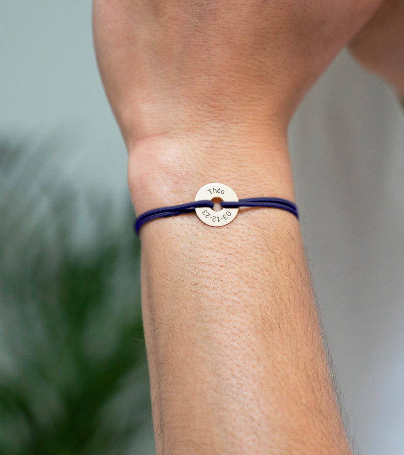 Avec une forme cible, ce bracelet personnalisé en 15mm, plaqué or, est agrémenté d'un cordon bleu marine.