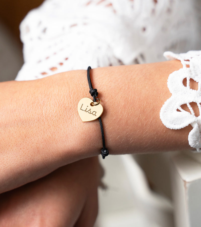 Bracelet cœur doré de 15 mm sur un cordon noir.