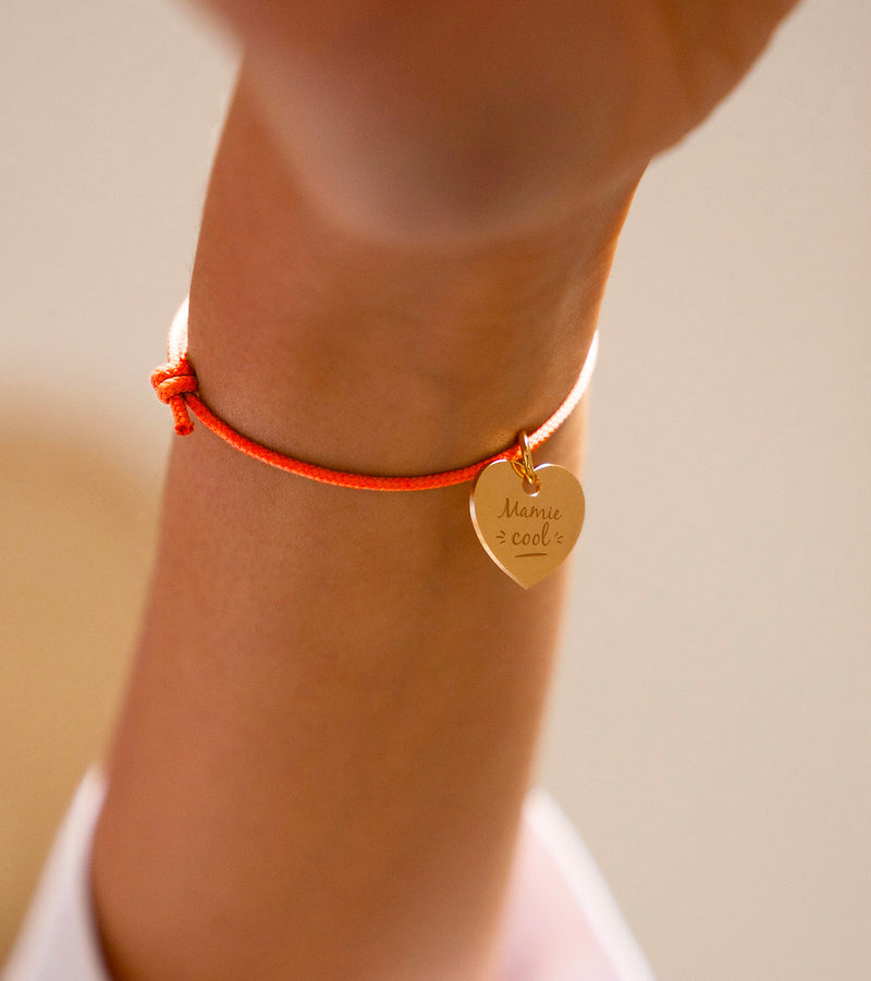Un bracelet en cordon orange fluo, rehaussé d'un charmant cœur plaqué or de 15mm