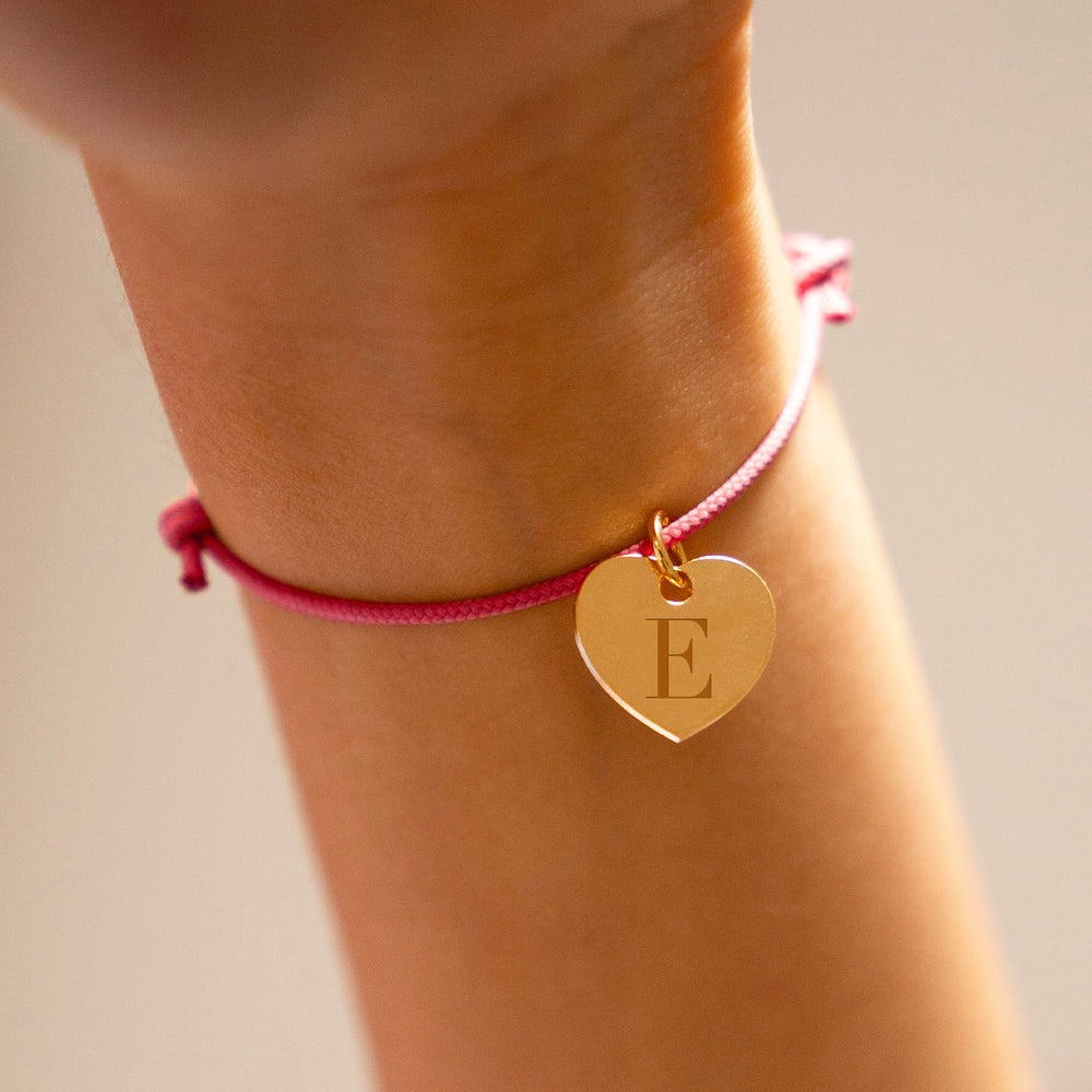 Un bracelet en plaqué or, sublimé par un pendentif cœur de 15mm, rehaussé d'un cordon rose vif.