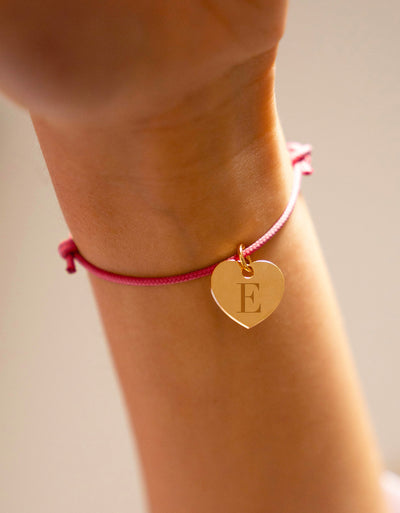Un bracelet en plaqué or, sublimé par un pendentif cœur de 15mm, rehaussé d'un cordon rose vif.