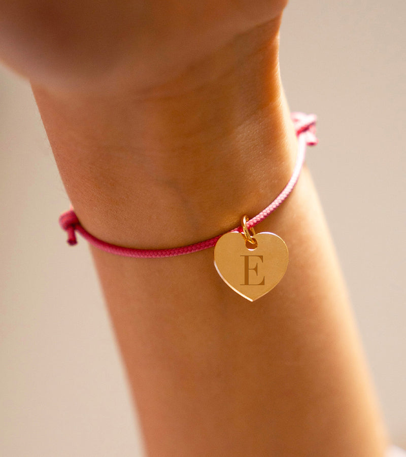 Un bracelet en plaqué or, sublimé par un pendentif cœur de 15mm, rehaussé d'un cordon rose vif.
