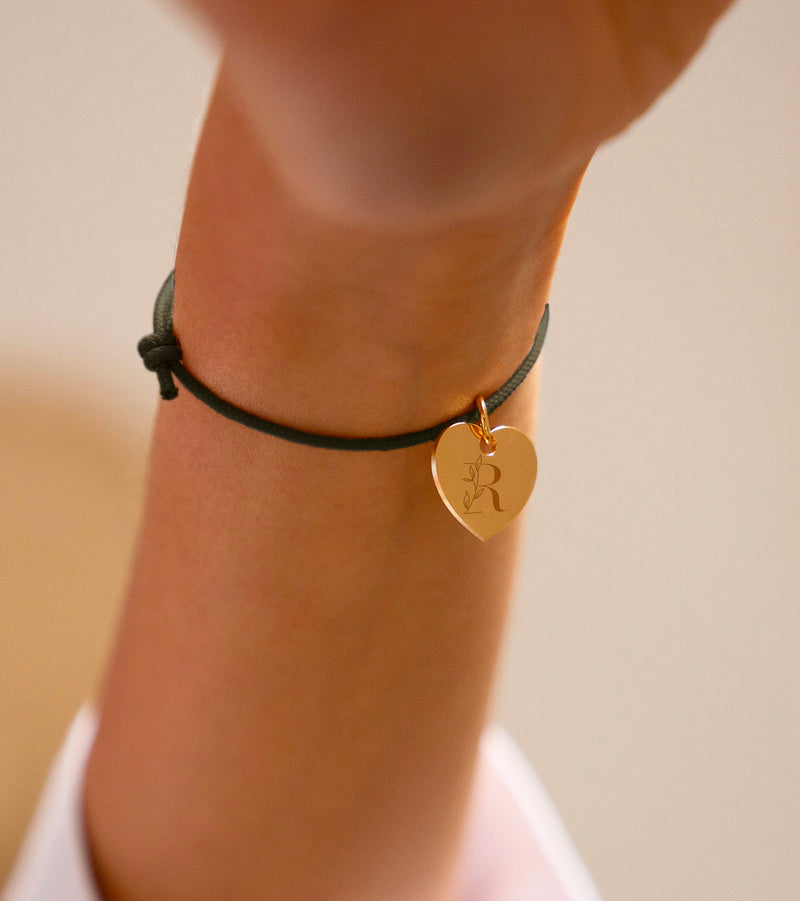 Un bracelet personnalisé avec un cœur de 15mm en plaqué or, attaché à un cordon kaki.