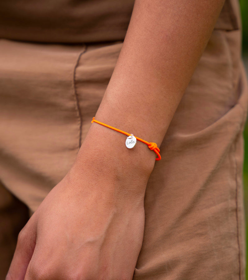Un bijou unique. Bracelet personnalisé avec une médaille en argent de 10mm et un cordon orange fluo.