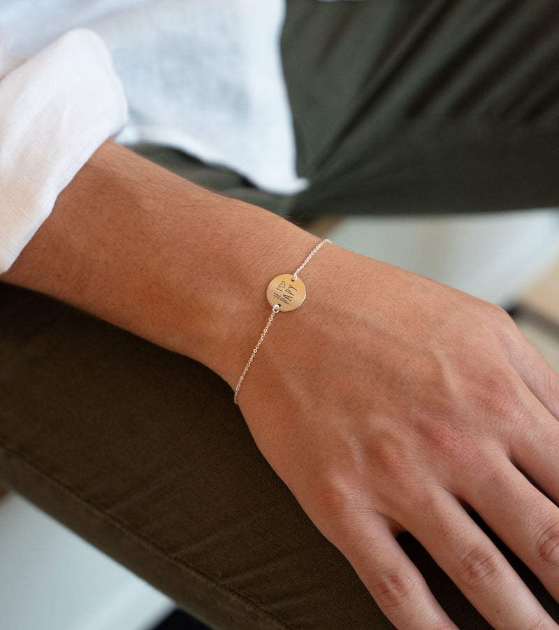 Un bracelet avec une médaille de 15mm personnalisée, présentant deux trous et une chaîne plate en argent