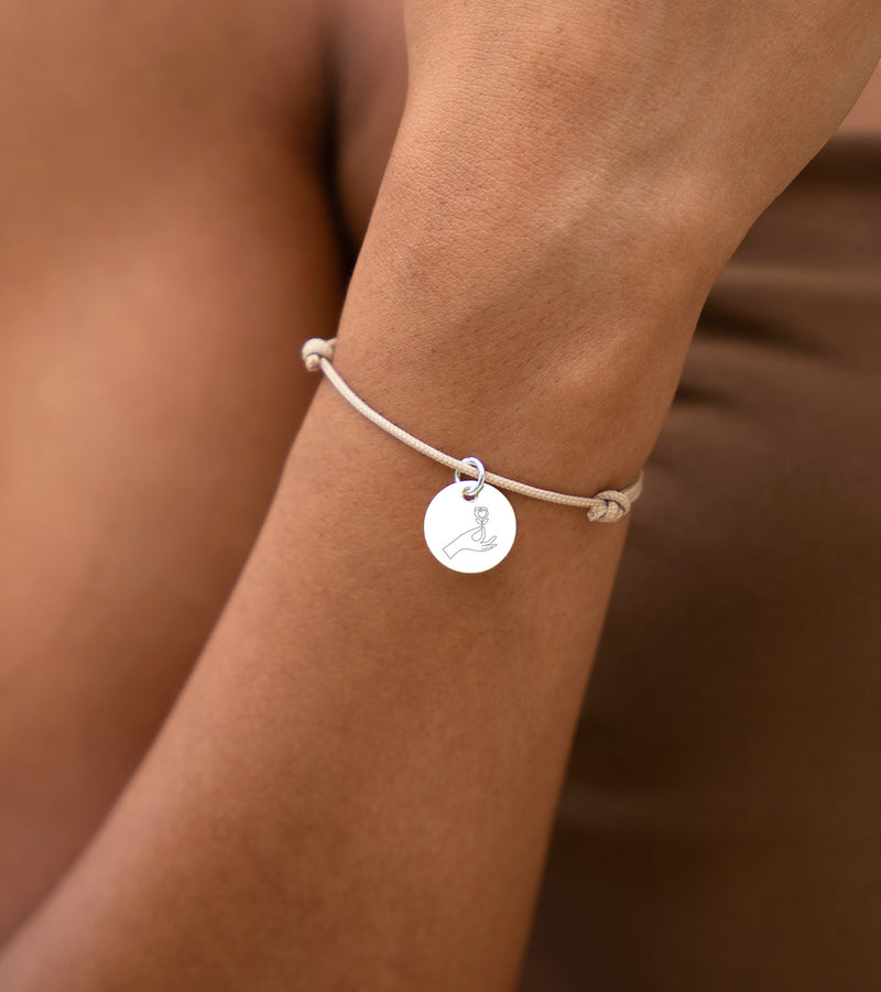 Un bracelet avec médaille de 15mm, personnalisable, sur un cordon beige.