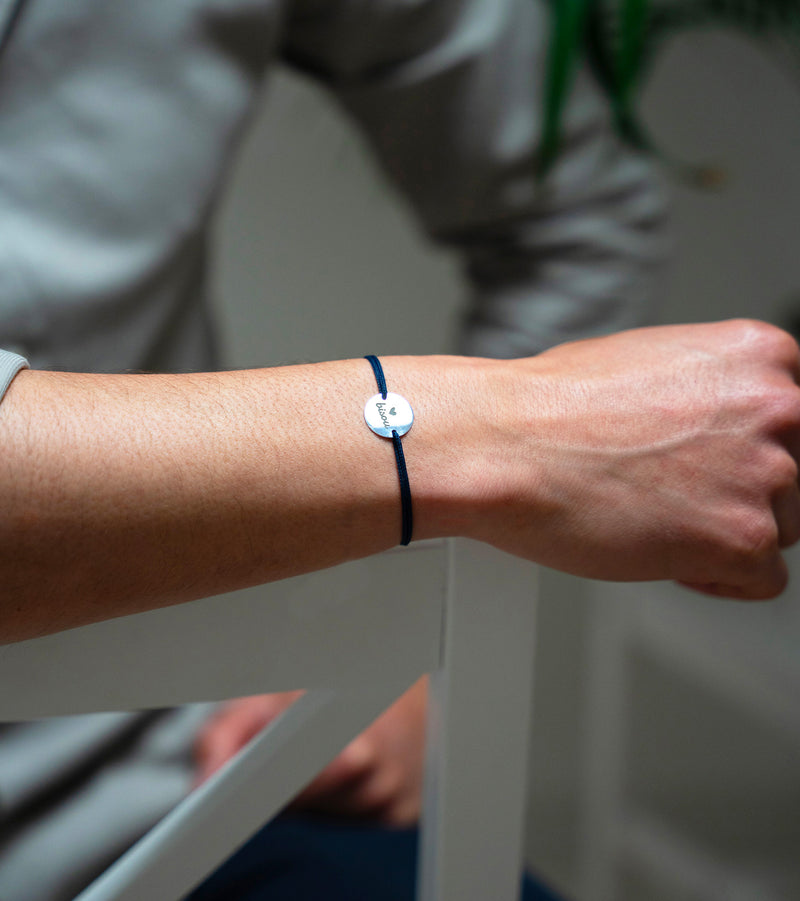 Un bracelet argenté de 15mm, orné d'une médaille personnalisée et rehaussé d'un cordon bleu marine.