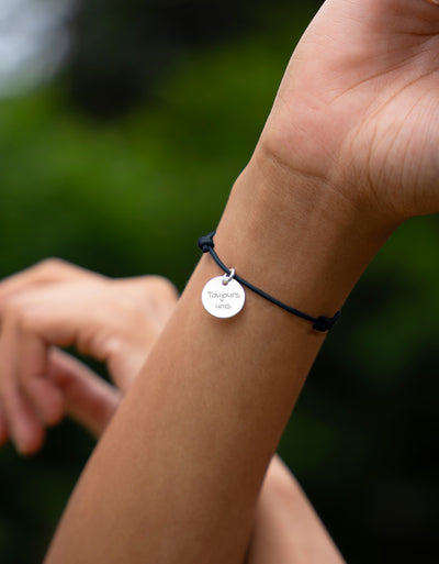 Un bracelet personnalisé en argent orné d'une médaille de 15mm, attaché avec un cordon bleu marine.