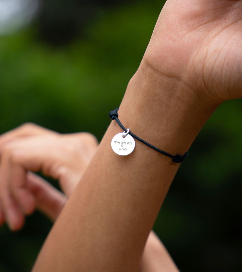 Un bracelet personnalisé en argent orné d'une médaille de 15mm, attaché avec un cordon bleu marine.