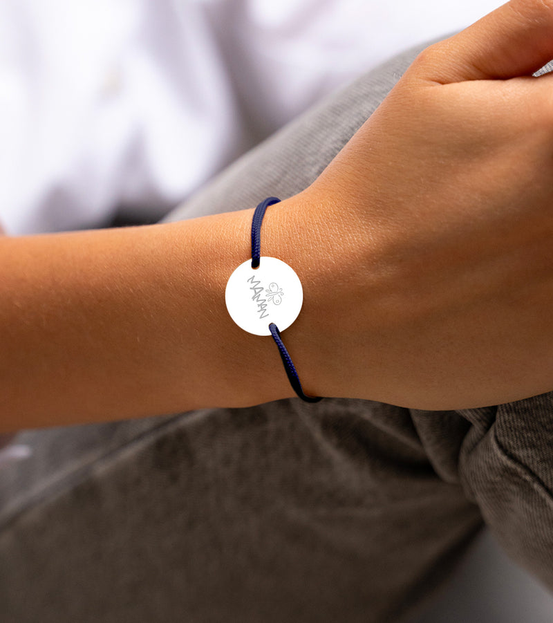 Le bracelet, avec sa médaille personnalisée en 20mm, présente deux trous argent et un cordon bleu marine.
