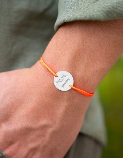 Orné d'une médaille, personnalisée 20mm, ce bracelet arbore deux trous argent et un cordon orange fluo.