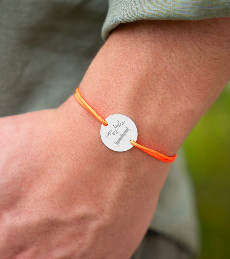 Orné d'une médaille, personnalisée 20mm, ce bracelet arbore deux trous argent et un cordon orange fluo.