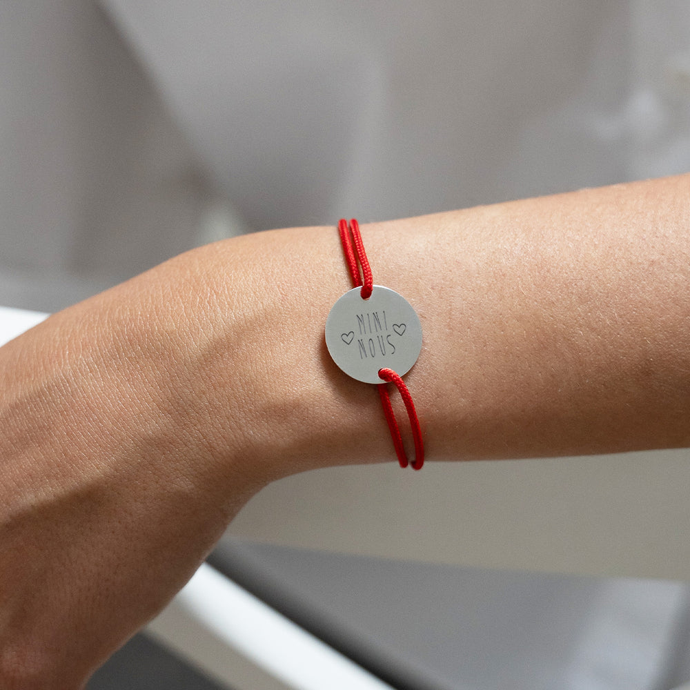 Un cordon rouge accompagne ce bracelet personnalisé,  avec une médaille en plaqué argent à deux trous.