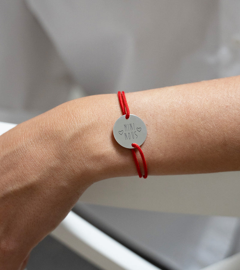Un cordon rouge accompagne ce bracelet personnalisé,  avec une médaille en plaqué argent à deux trous.
