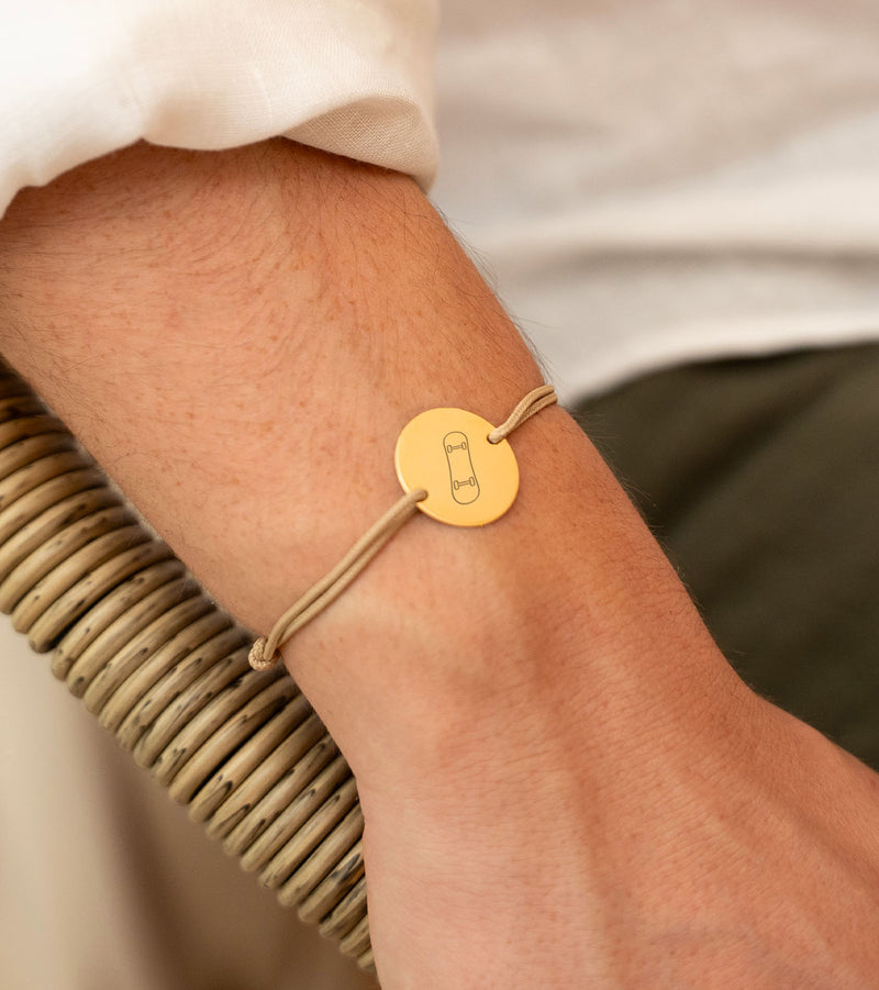 Un bracelet unique avec une médaille de 20mm, deux trous en plaqué or et un cordon beige, parfait pour exprimer votre style.