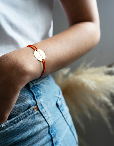 une médaille personnalisée en 20mm, ce bracelet possède deux trous en plaqué or et un cordon orange fluo