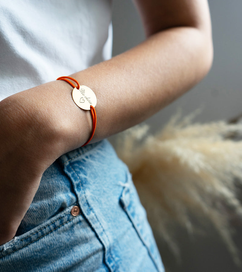 une médaille personnalisée en 20mm, ce bracelet possède deux trous en plaqué or et un cordon orange fluo