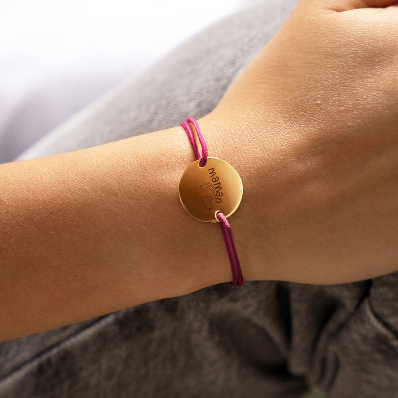 Un bracelet médaille en 20mm, doté de deux trous en plaqué or et d'un cordon rose fuchsia.