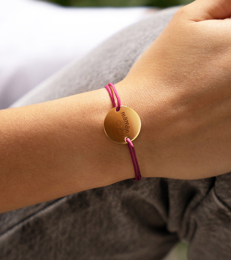 Un bracelet médaille en 20mm, doté de deux trous en plaqué or et d'un cordon rose fuchsia.