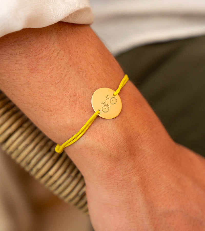 Un bijou qui roule avec vous ! Ce bracelet en médaille plaqué or et cordon jaune est fait pour les amoureux du vélo. Faites graver votre message et affichez votre style tout en pédalant !