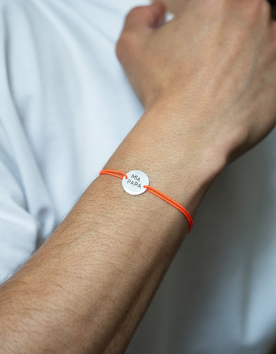 Un bracelet argenté de 15mm, avec deux trous distinctifs pour un cordon orange fluo.