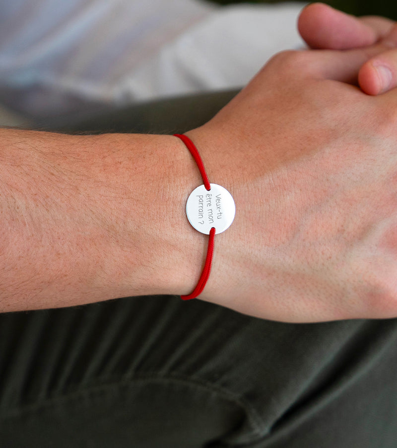 Médaille personnalisée argentée de 15mm avec 2 trous, sur un bracelet cordon rouge, pour un look distinctif.