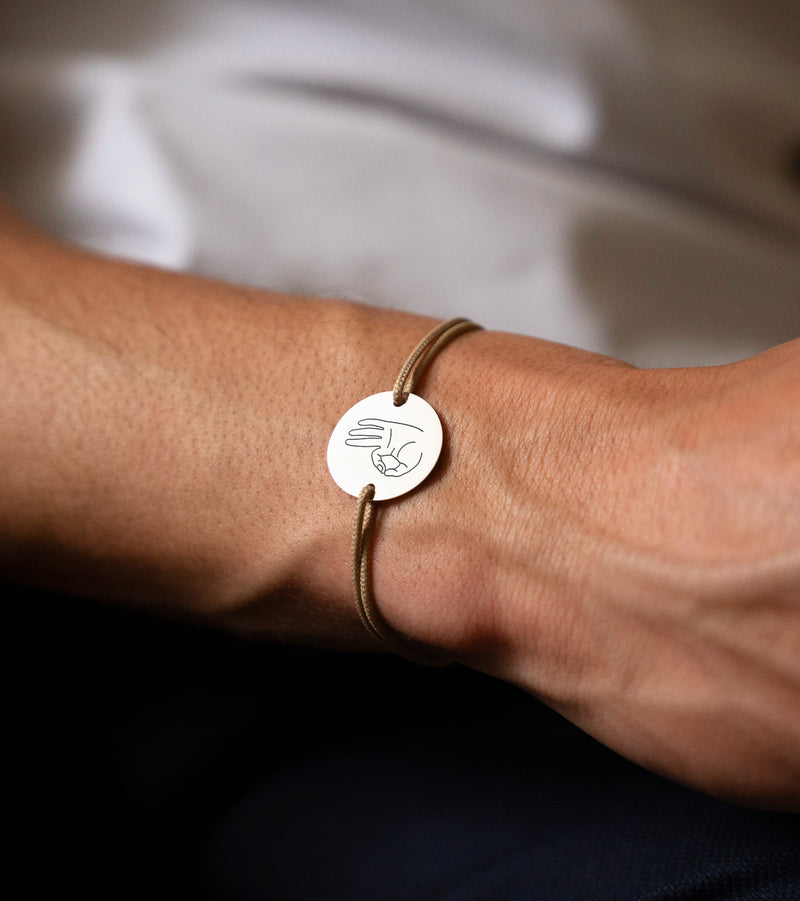Arborant une médaille personnalisée en 20mm, ce bracelet comprend deux trous en plaqué argent et un cordon marron clair.