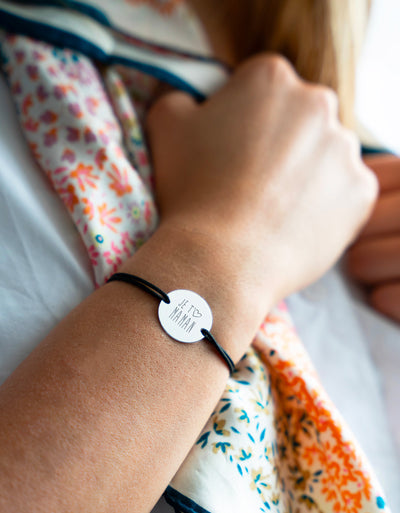 Ce bracelet, arborant une médaille argentée personnalisée de 20mm, deux trous pratiques, et un cordon noir