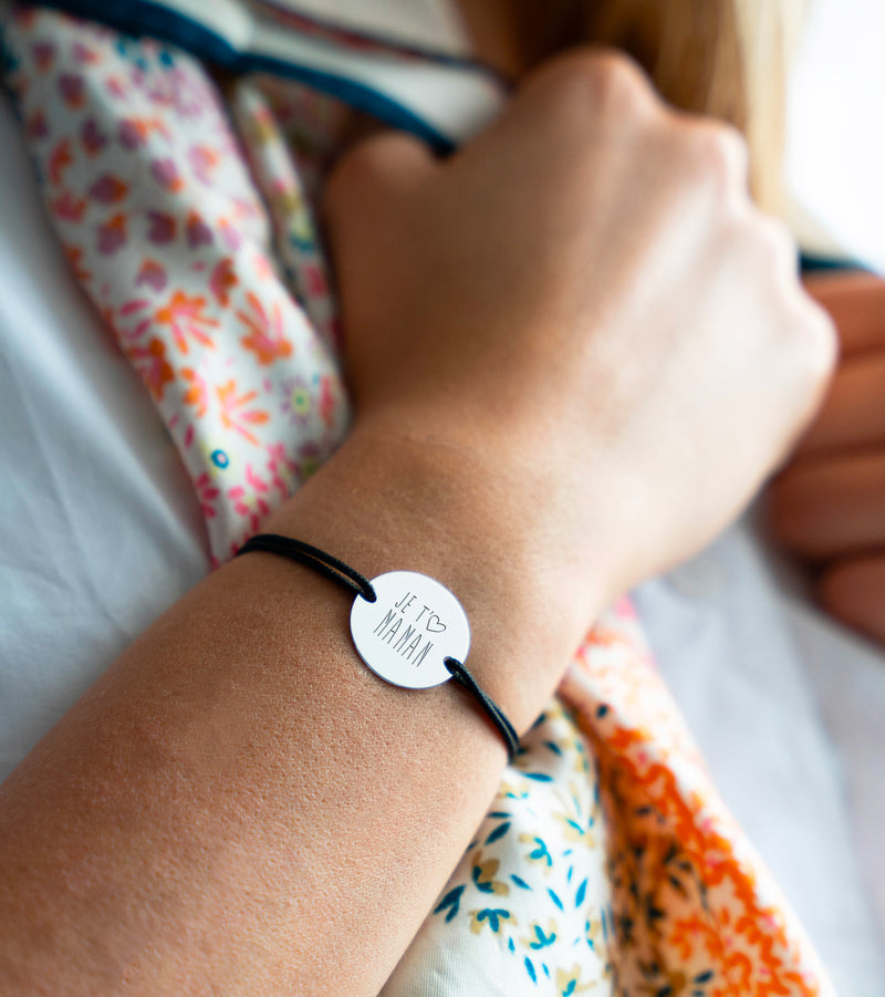 Ce bracelet, arborant une médaille argentée personnalisée de 20mm, deux trous pratiques, et un cordon noir