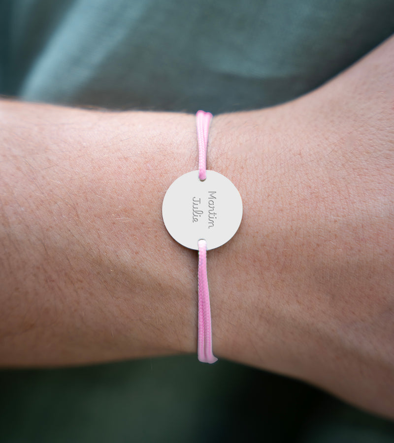 Doté d'une médaille et personnalisé en 20mm, ce bracelet intègre deux trous argent et un cordon rose.